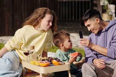 Smiling family having a picnic with fresh fruit on a sunny day, capturing memories.