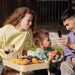 Smiling family having a picnic with fresh fruit on a sunny day, capturing memories.